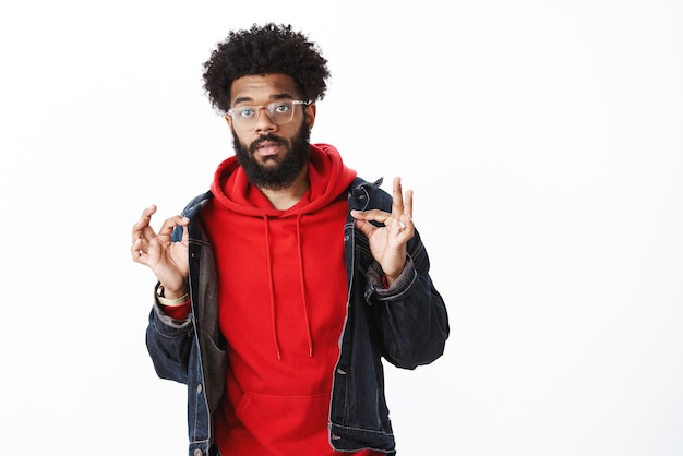 african-american male with beard, pierced nose and afro haircut showing okay gesture with orbs and looking careless, unbothered.