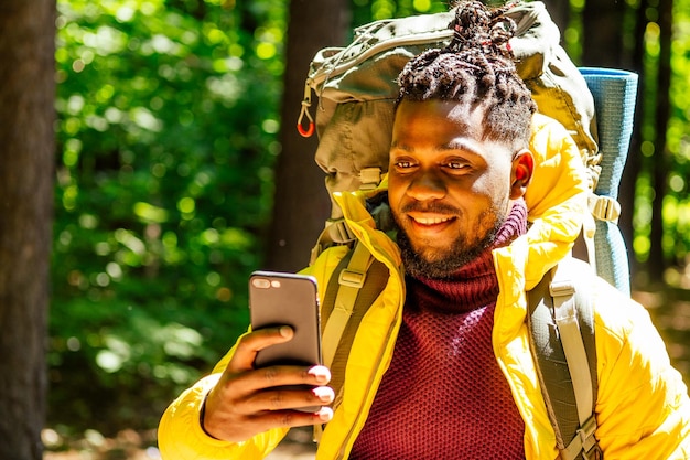 African american male in yellow jacket looking at phone location map online