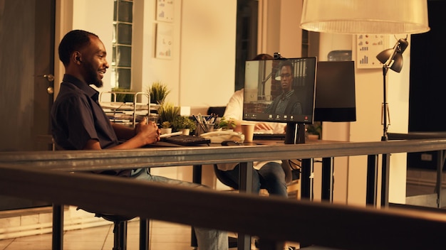 African american man attending conference meeting with\
colleague, talking on online videocall with webcam. using computer\
to talk to remote web videoconference, teleconference call.