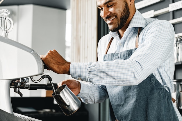 Афро-американский мужчина-бариста готовит кофе на профессиональной кофемашине