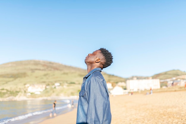 Uomo afroamericano che respira aria fresca in spiaggia in una giornata di sole