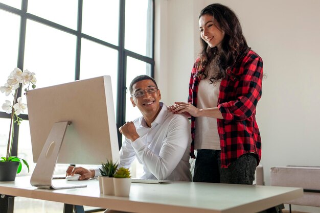 African american man in business clothes and glasses sits and works at computer with his wife