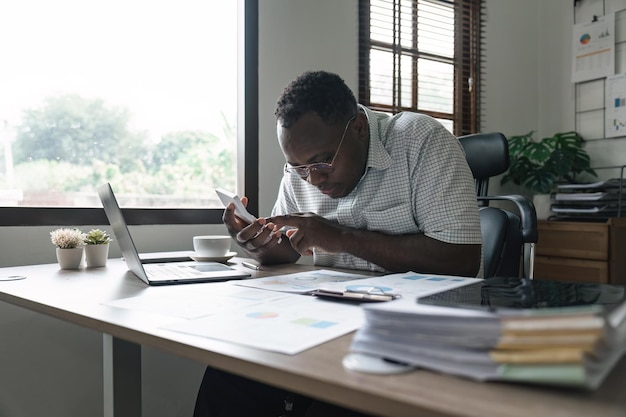 African American man calculating using machine managing household finances at home focused biracial male make calculations on calculator account taxes or expenses