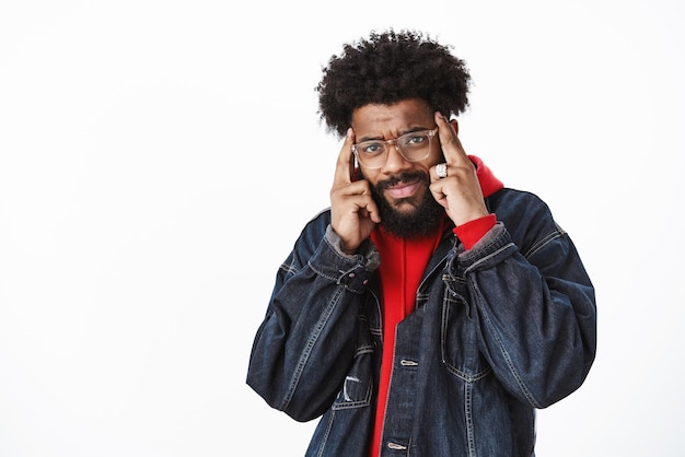 african american man cannot focus having headache or migraine holding fingers on temples frowning and grimacing from pain posing on gray.