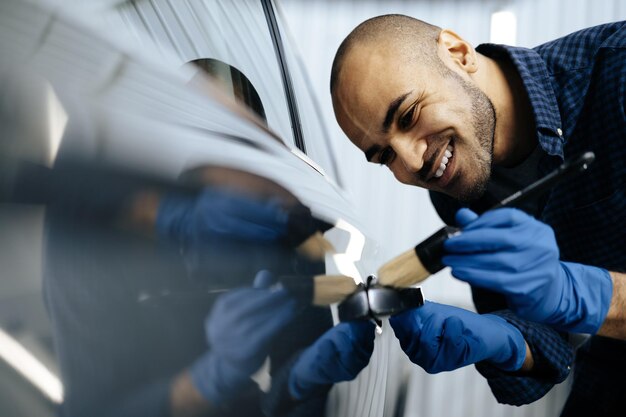 Photo african american man car service worker applying nano coating on a car