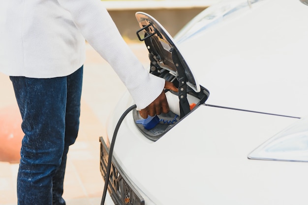 African American man charging his electric car.