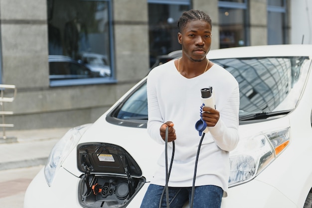 Uomo afroamericano che carica la sua auto elettrica.