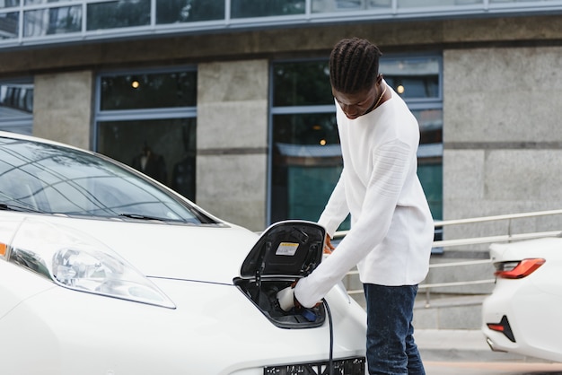 電気自動車を充電しているアフリカ系アメリカ人の男。