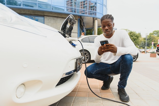 電気自動車を充電しているアフリカ系アメリカ人の男。