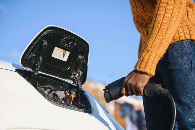 電気自動車を充電しているアフリカ系アメリカ人の男。