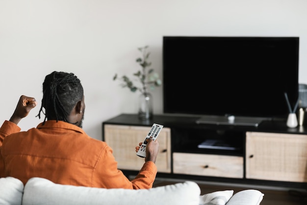 African american man cheerfing for favourite team watching sports game on tv television set with empty screen