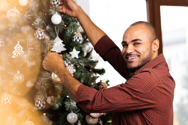 Photo african american man decorating christmas tree at home