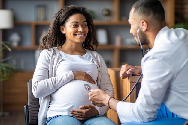 Photo african american man doctor doing checkup for pregnant lady