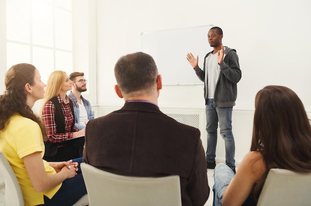 Photo african-american man doing presentation in office, copy space. startup business meeting, sharing new ideas to partners, teamwork concept