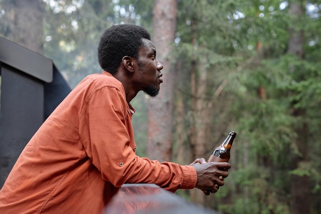 African american man drinking beer at picnic in the forest