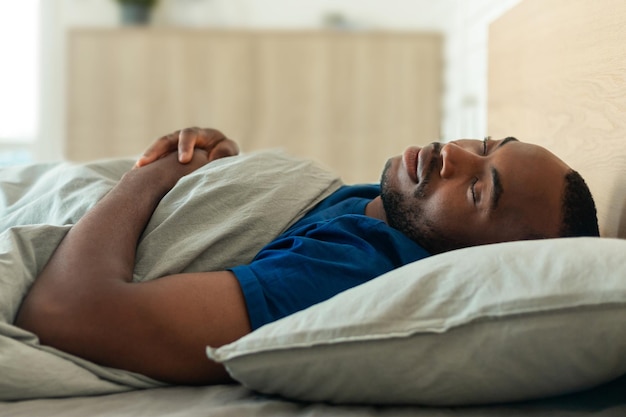 Photo african american man enjoying healthy sleep resting lying in bedroom