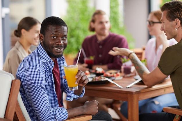 Афро-американский мужчина наслаждается обедом с друзьями в кафе