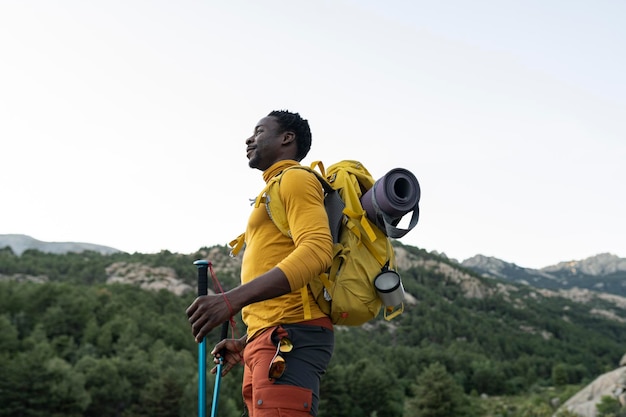 アフリカ系アメリカ人の男性が山の頂上に立って山の景色を楽しんでいる