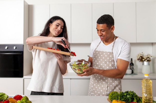 african american man and european woman preparing vegetable and greens salad together