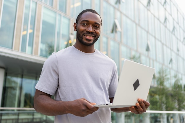 Photo african american man freelancer using laptop typing chatting on urban street in city guy having