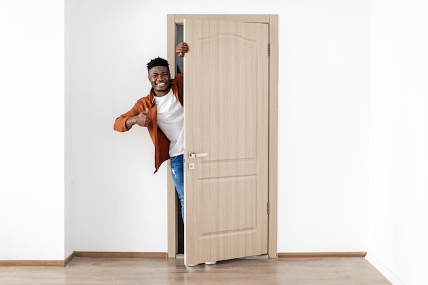 African american man gesturing thumbs up opening door of house