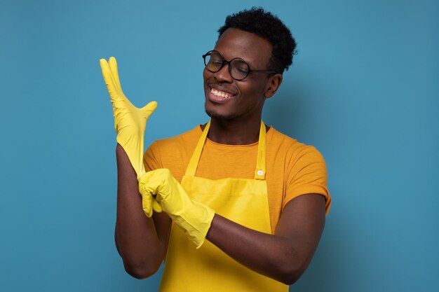 African american man in glasses putting on yellow rubber gloves for cleaning