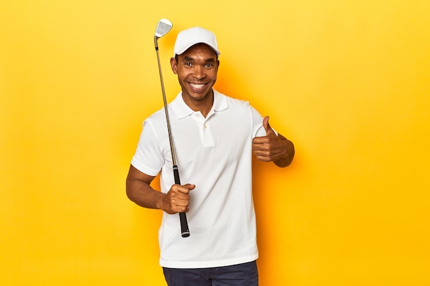 アフリカ系アメリカ人ゴルファー黄色いスタジオの背景で笑顔で親指を上げています