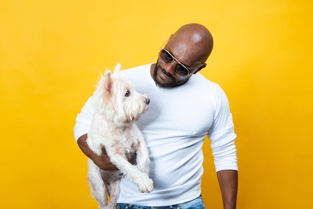 African American man in good physical shape on yellow background with his dog