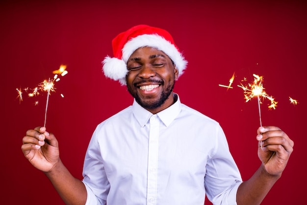 African american man holding a burning stick of dynamite in studio red background