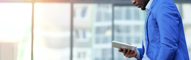 African american man holding white tablet walks in street