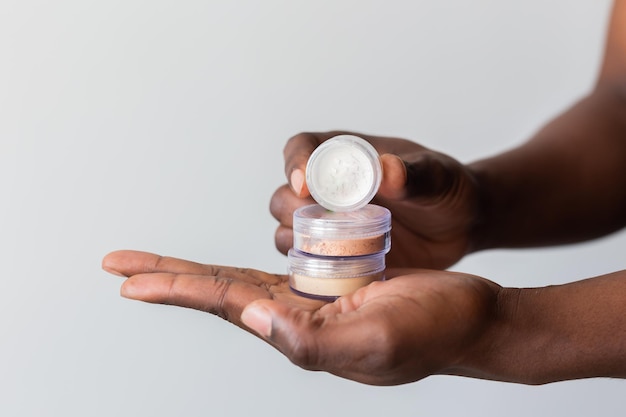 African american man holds mineral facial powder for perfect makeup for women male makeup artist and