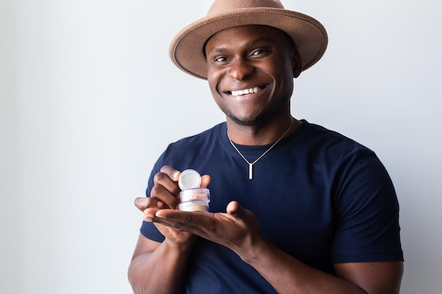 African american man holds mineral facial powder for perfect makeup for women male makeup artist and