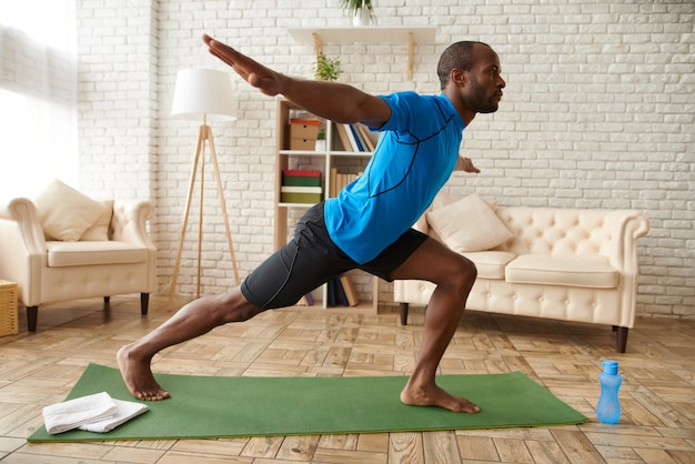 African American man is practicing advanced yoga at home.