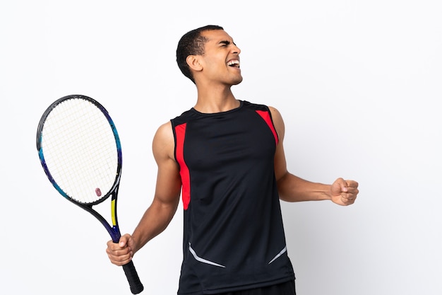 African American man over isolated white background playing tennis and celebrating a victory