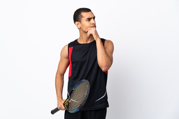 African American man over isolated white wall playing tennis and thinking