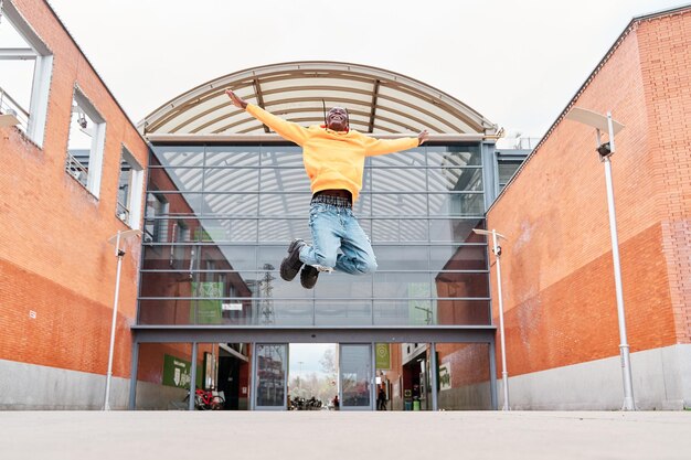 African american man jumping celebrating success in the city handsome young man in casual clothes jumping with excitement