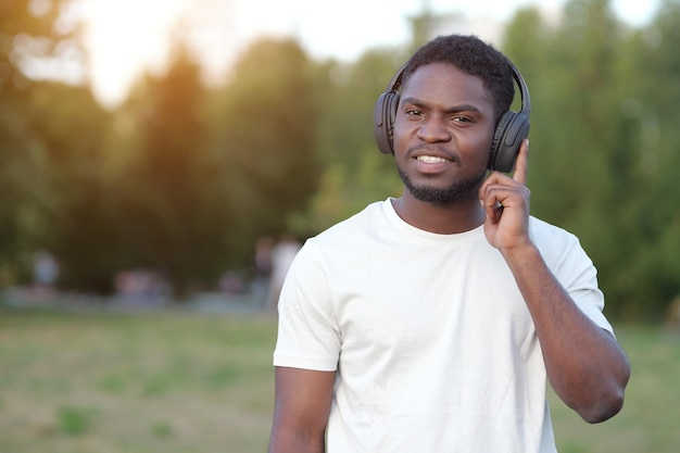 アフリカ系アメリカ人男性が公園でヘッドフォンで音楽を聴く