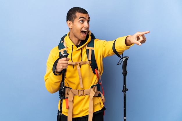 African american man met rugzak en trekking stokken over geïsoleerde muur weg wijzen