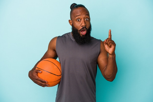 いくつかの素晴らしいアイデア、創造性の概念を持っている青い背景に分離されたバスケットボールをしているアフリカ系アメリカ人の男。