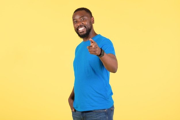 African american man pointing finger at camera over yellow\
background