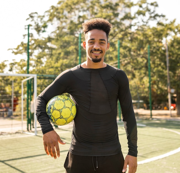 Foto uomo afroamericano in posa con un pallone da calcio