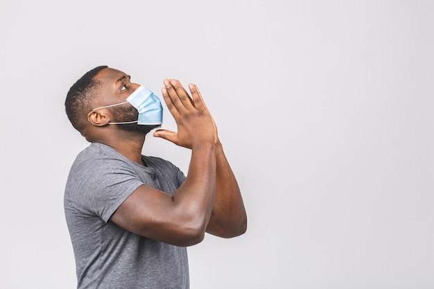 African american man praying wearing hygienic mask to prevent infection, airborne respiratory illness