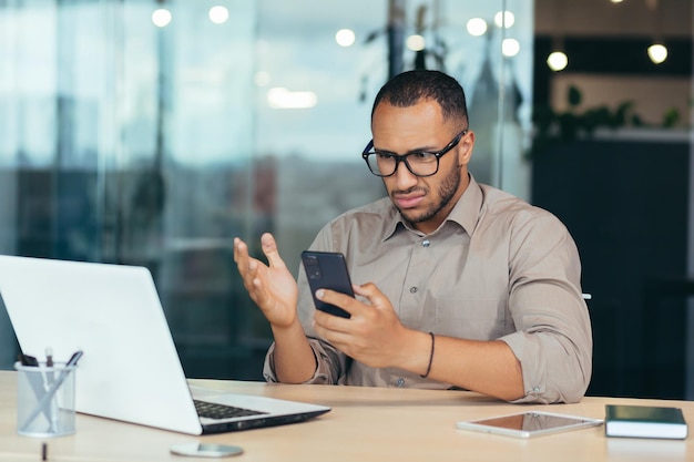 African american man received bad news notification online from\
phone businessman in shirt working