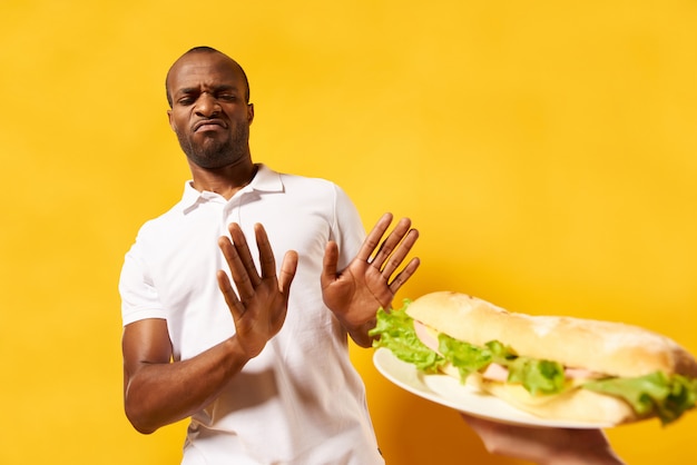 African American man refuses large big sandwich.