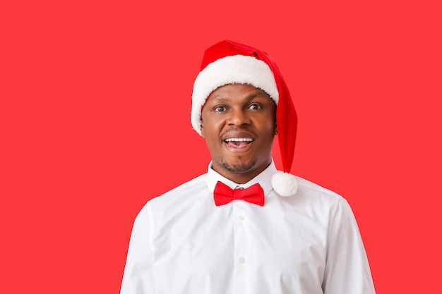 African-American man in Santa hat on color