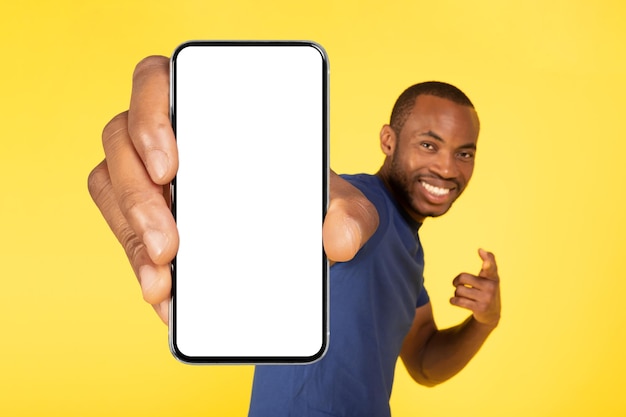 African American Man Showing Huge Cellphone Blank Screen Yellow Background