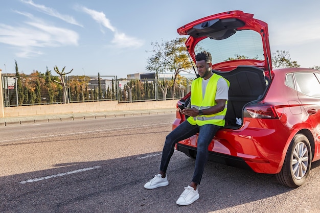 African American Man Sitting on the Back of a Red Car