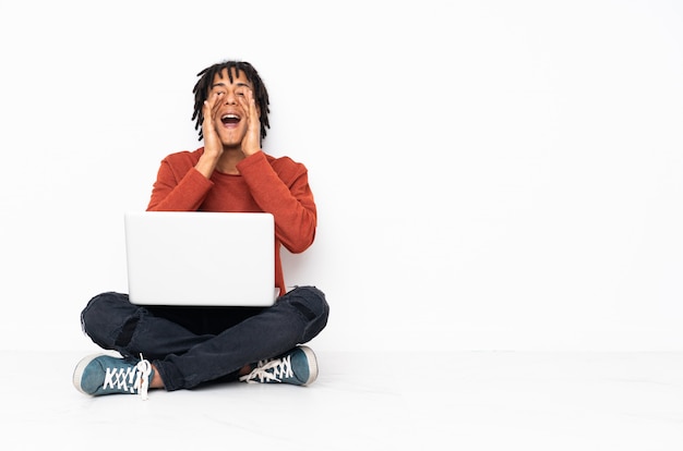 African American man sitting on the floor holding a computer