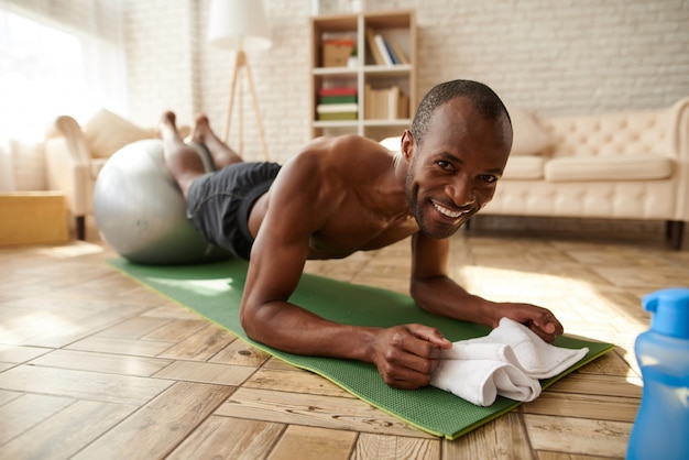 African American man smile performs plank.