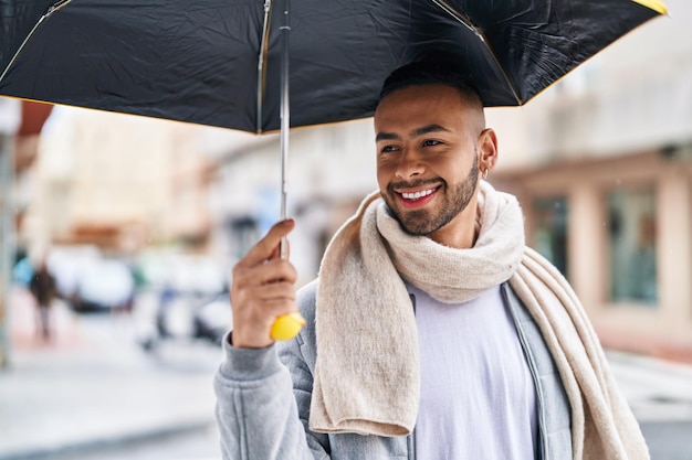 写真 通りで傘を持って自信を持って微笑むアフリカ系アメリカ人男性